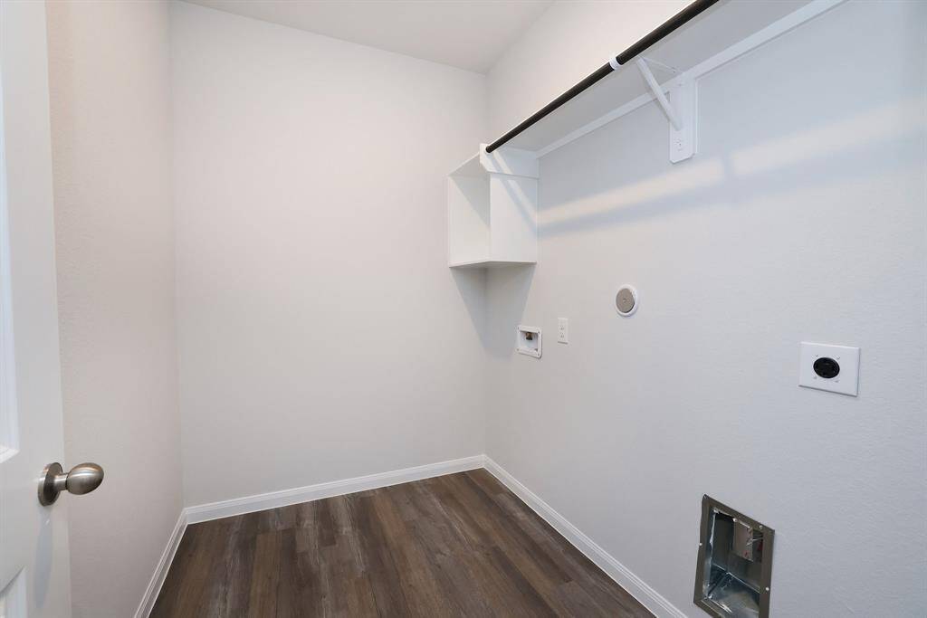 Lessen the chore of laundry with this bright utility room with hookups for a washer and dryer, and a shelf with a hanging rod for storage.