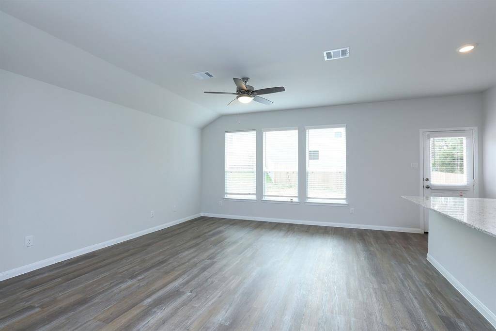The main living area is drenched in natural lighting from the wall of windows dressed in blinds.