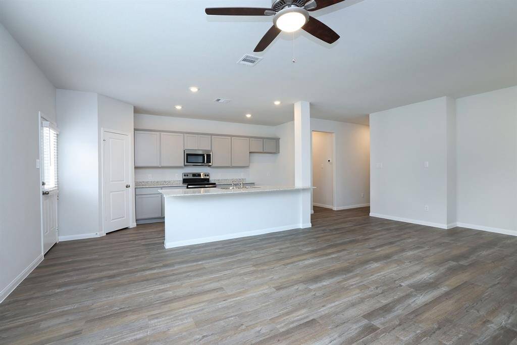 The spacious kitchen features modern gray cabinetry, granite counter tops, an island with sink and large pantry.