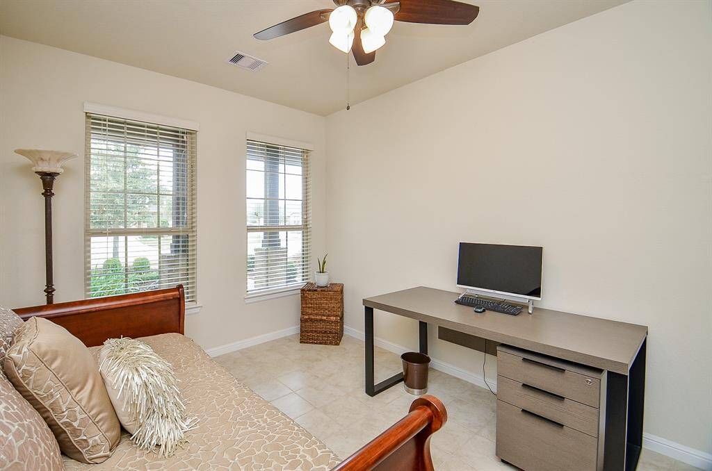Tile flooring adds durability and style, while a high ceiling with a fan enhances the airy atmosphere. Large windows flood the space with natural light.