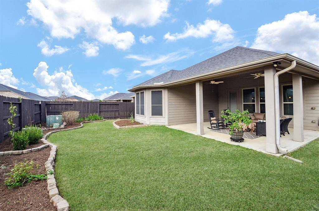 The patio offers a serene view of the lush, expansive backyard, which is fully fenced for privacy and security.