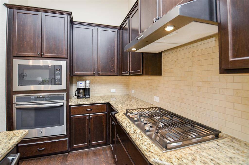 State-of-the-art stainless steel appliances elevate the kitchen, including a dishwasher, built-in oven and separate microwave for effortless cooking, and a 5-burner gas cooktop complete with a sleek vent hood.