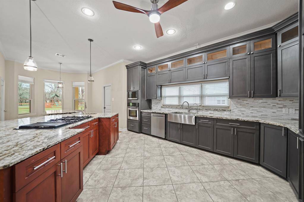 The generously sized kitchen boasts custom maple cabinetry, stainless steel appliances, and  farmhouse sink. An inviting island with a casual seating area accented by stylish pendant lighting.