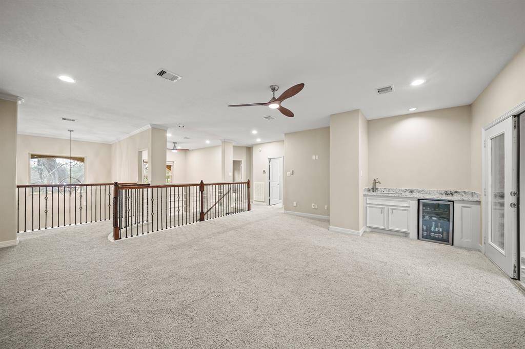 The game room while staged as a living area, offers versatile entertainment options, a wet bar and wine fridge, an ideal space for relaxation and fun.
