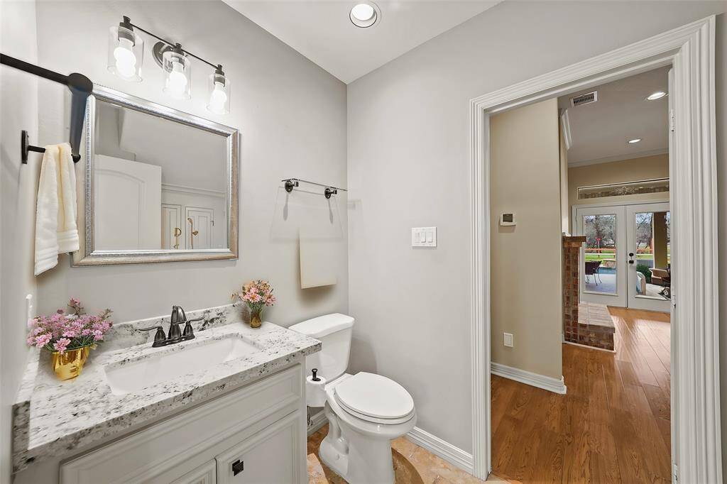 The second formal area is staged as a sophisticated office, featuring rich wood floors and glass French doors for privacy. A large window fills the space with natural light, creating a bright and productive atmosphere.