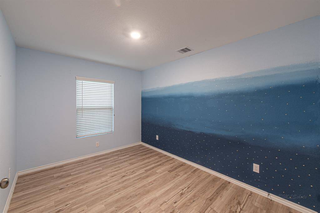 This bedroom features a unique blue accent wall, vinyl flooring, and is pre-wired for a ceiling fan.