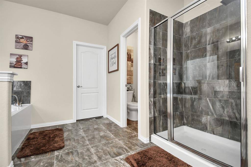The spacious master bathroom features beautiful white cabinets topped with the same beautiful Quartz countertop surrounding the dual sinks and vanity area. It has a separate garden tub and shower which has been upgraded with a beautiful tile.