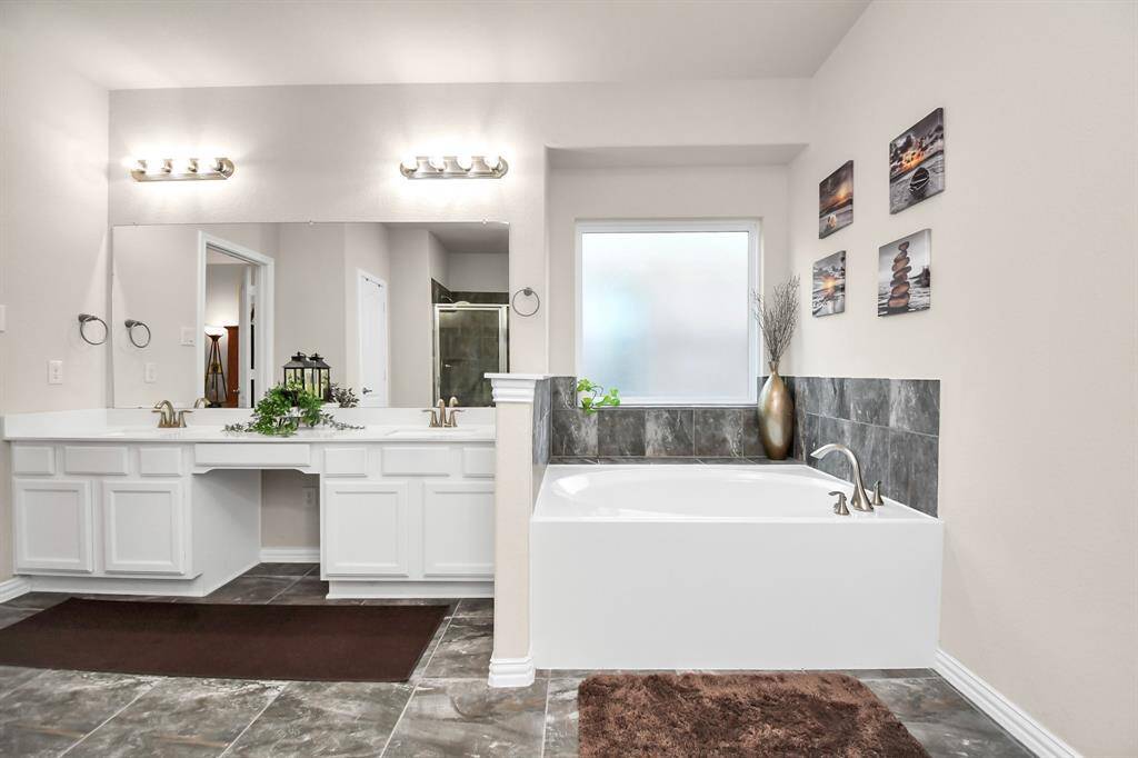 The spacious master bathroom features beautiful white cabinets topped with the same beautiful Quartz countertop surrounding the dual sinks and vanity area. It has a separate garden tub and shower which has been upgraded with a beautiful tile.