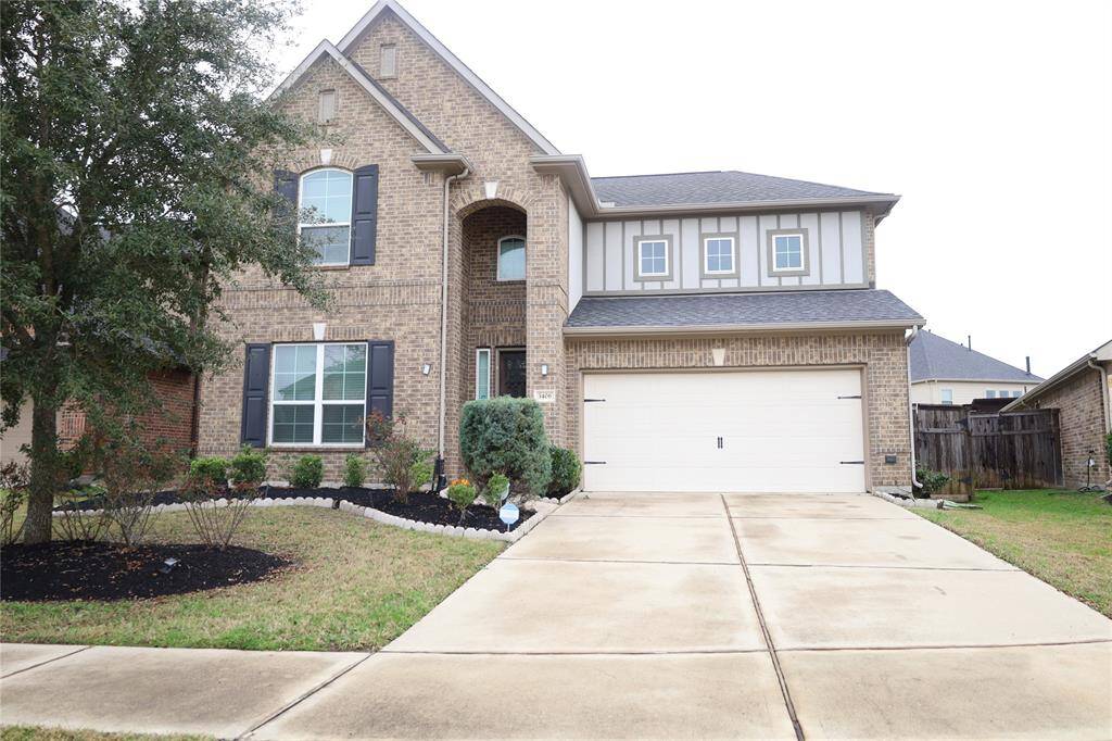 This is a two-story brick home with a gable roof and a two-car garage.