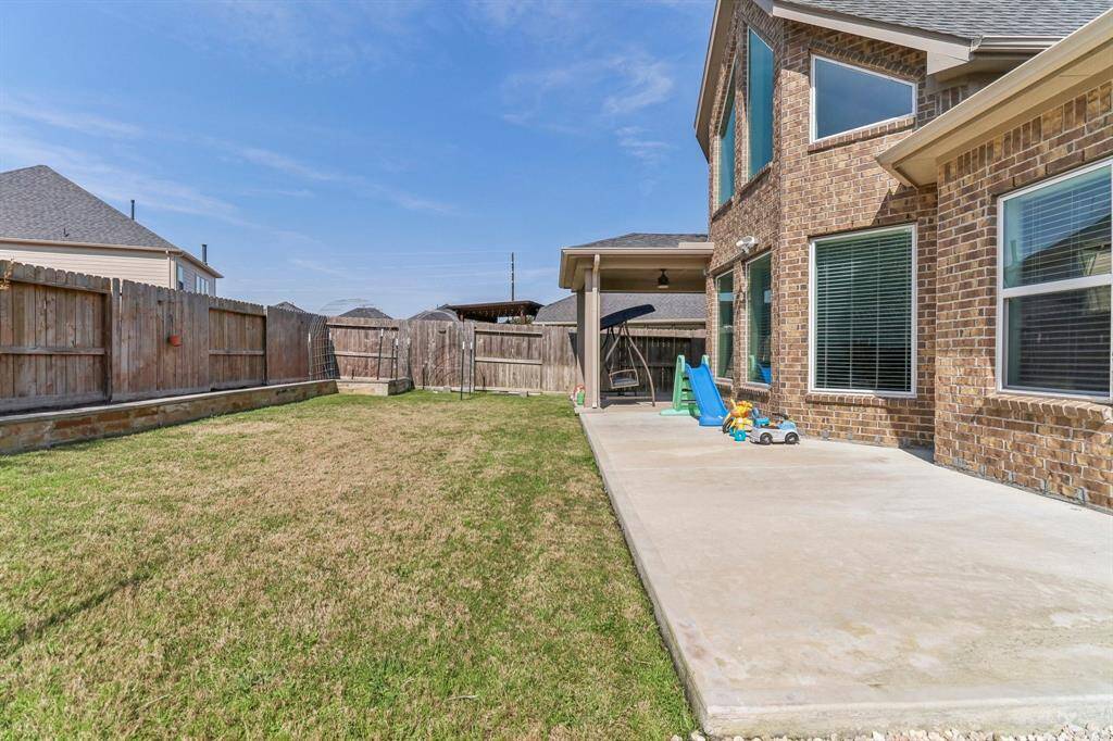 Spacious backyard with a neatly maintained lawn, wooden fence for privacy, and trellis structures, perfect for gardening or outdoor activities.