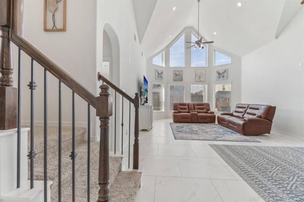 This spacious living area features high ceilings, an open layout, and elegant tile flooring.