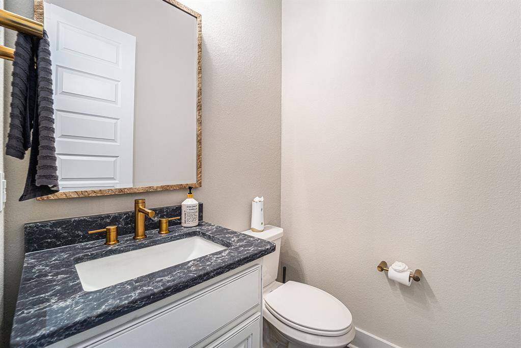 Stylish downstairs bathroom featuring exquisite Silestone countertops, complemented by an upgraded mirror and light fixture for a modern, refined touch.
