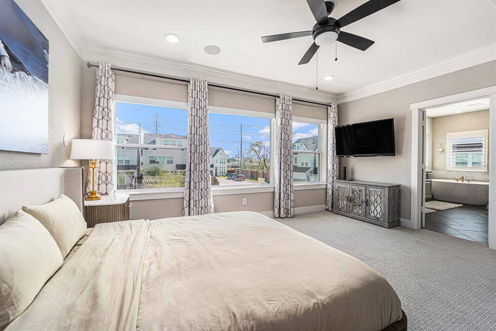 Bathed in natural light from expansive windows, this spacious room offers a warm, welcoming feel. Double doors lead into the serene bathroom, adding a sophisticated touch.