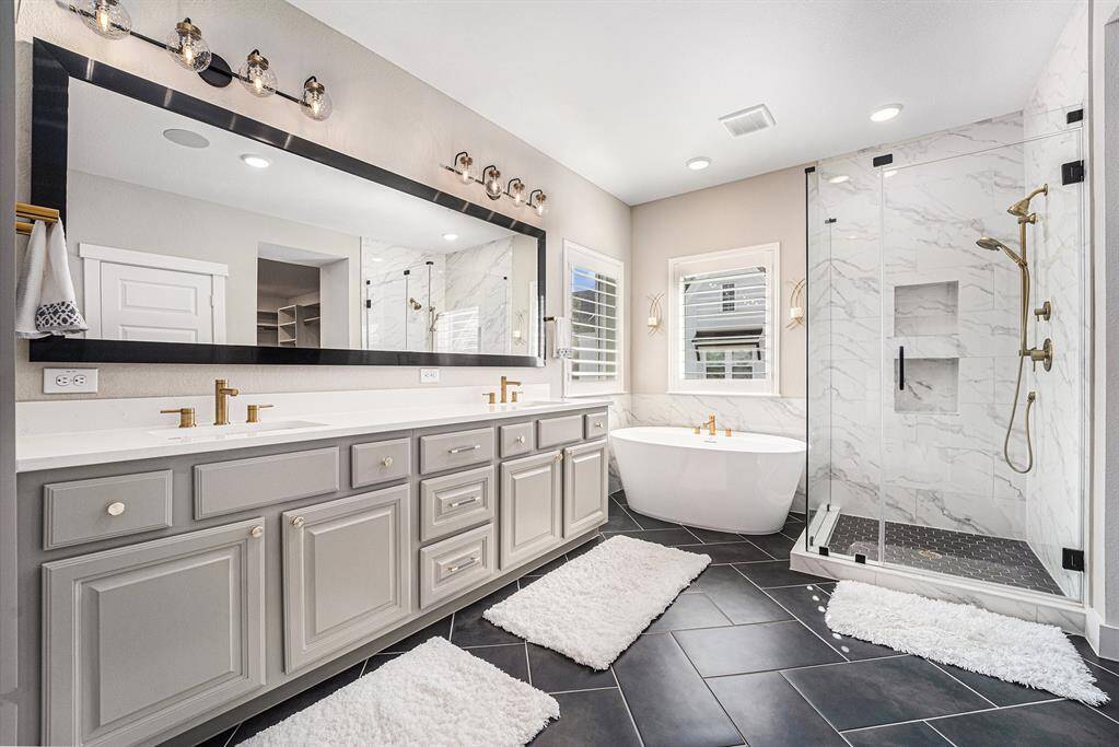 Luxurious primary bathroom featuring a stunning freestanding tub, elegant marble countertops with gold hardware, and a built-in sound system for a spa-like experience.