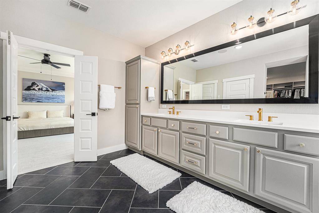 Beautiful herringbone floors enhance the elegance of the primary bath, while ample storage adds both convenience and functionality to this stunning space