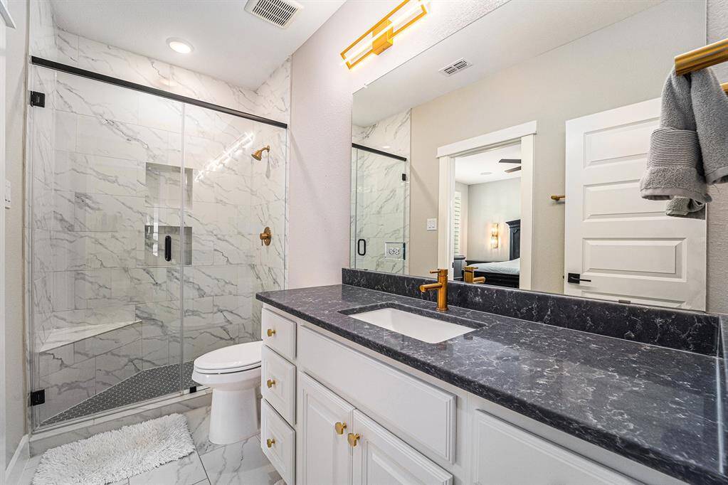 Upstairs bath featuring a luxurious shower with tile extending to the ceiling, complemented by sleek Silestone countertops and elegant marble floors, offering a refined and relaxing environment.