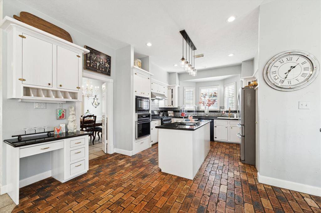 Planning center with desk and cabinets in kitchen. Island kitchen with plenty of counter space. Plantation shutters at window.