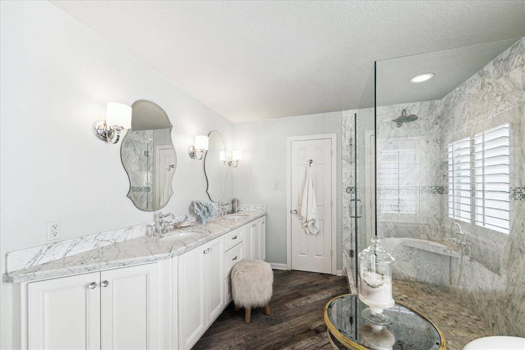 Another view of the primary bathroon. Double sinks. White cabinets. Large glass walk-in shower.