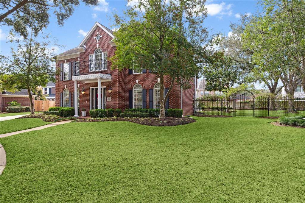 Front yard. Wrough iron fencing on the side. Lush landscaping. Trees!!