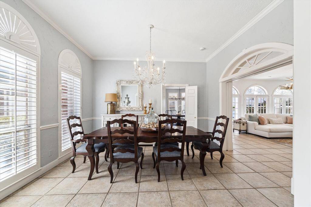 Elegant formal dining has tile flooring, pocket doors, and plantation shutters with sunburst on top.
