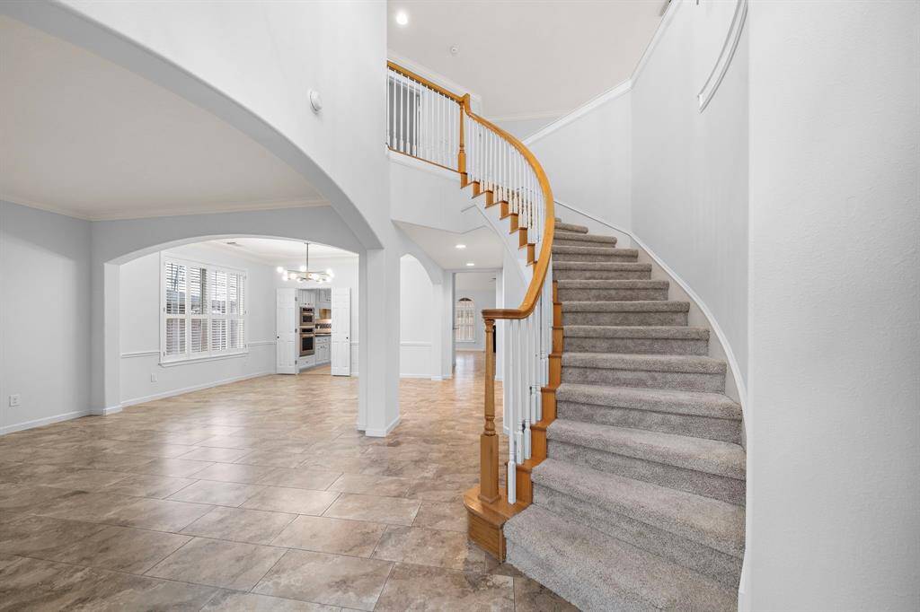 Step into elegance with this grand entryway featuring a sweeping staircase and an open-concept floor plan. Soaring ceilings, graceful archways, and an abundance of natural light create a sophisticated yet welcoming atmosphere.