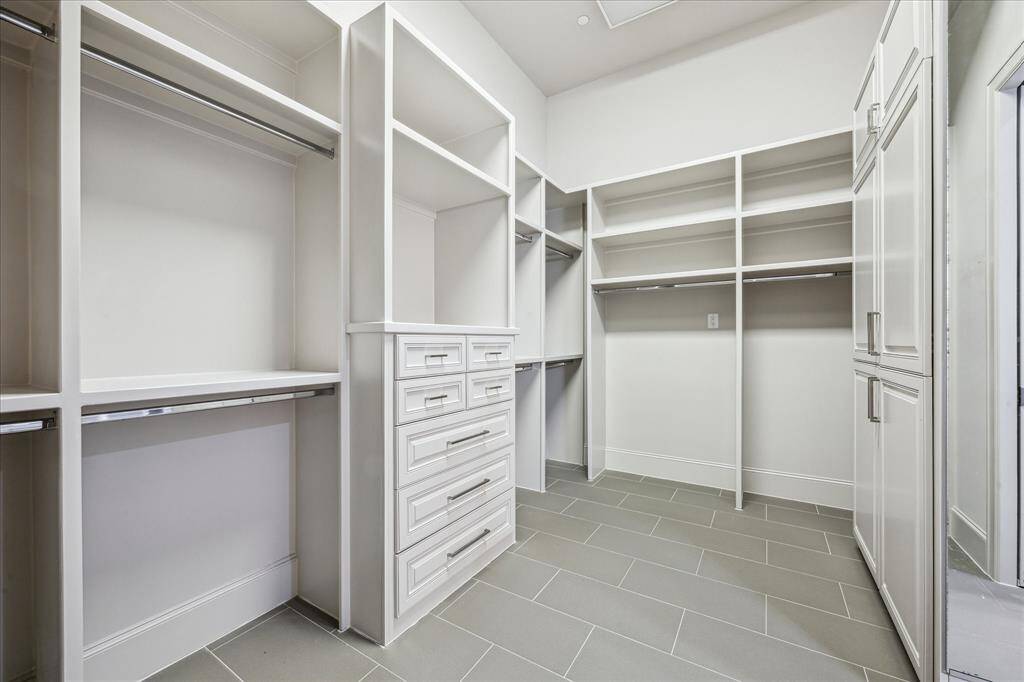 PRIMARY CLOSET: This expansive primary closet offers the ultimate in storage and organization, featuring custom shelving, ample hanging space, and thoughtfully designed built-ins. With its generous layout, this luxurious closet provides a boutique-style experience, making it easy to keep everything beautifully arranged while adding a touch of everyday elegance.