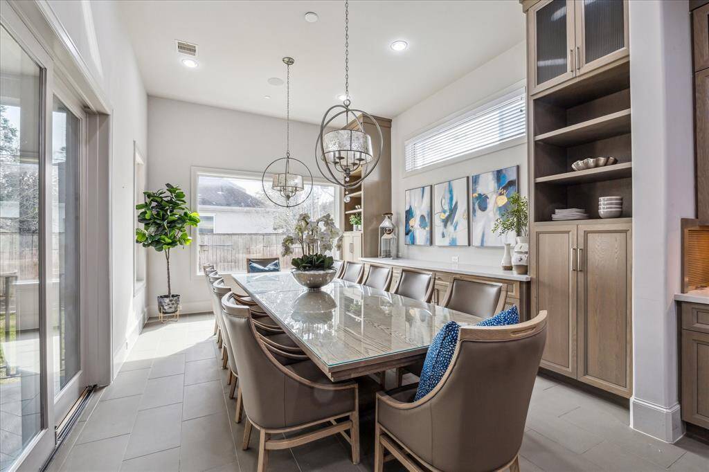 DINING ROOM: This grand dining room exudes timeless elegance, designed to impress with every detail. Featuring soaring ceilings, stunning light fixtures, and a beautifully crafted built-in buffet wall for effortless serving, this space is ideal for both formal entertaining and intimate gatherings. The expansive window allows natural light to flood the room, highlighting the luxurious finishes and architectural features. With its blend of grandeur and functionality, this dining room is a true showstopper!