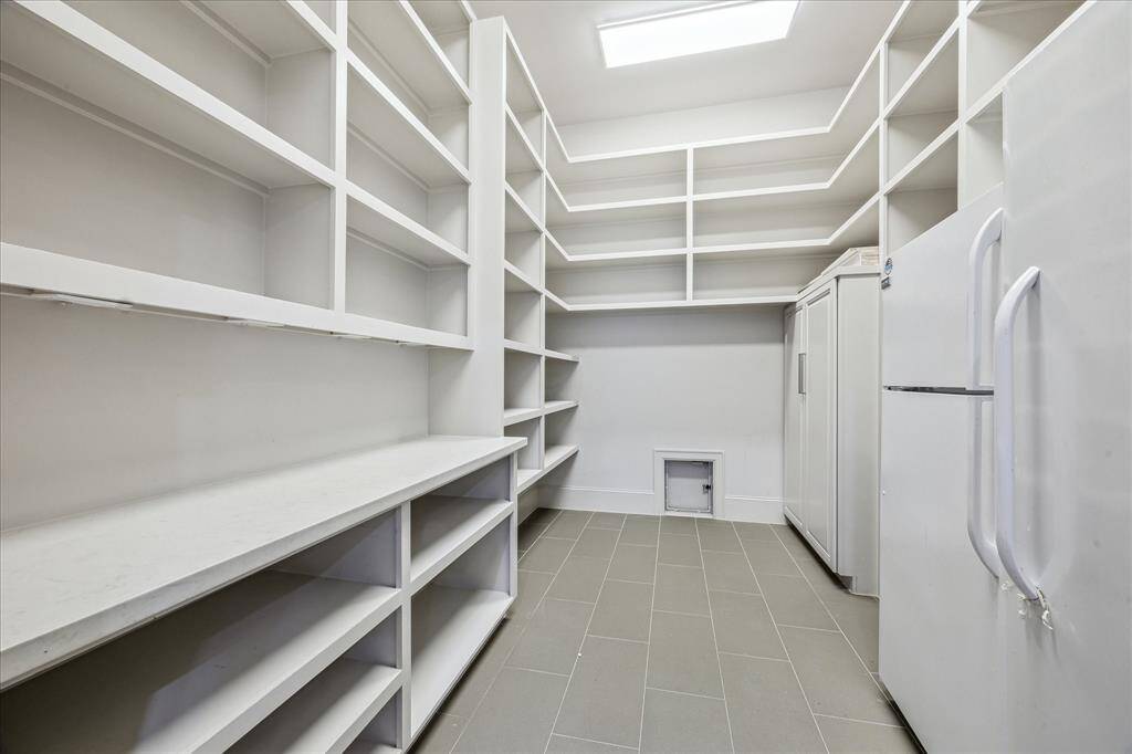 PANTRY: A dream pantry for the organized chef! This spacious walk-in pantry offers abundant storage solutions, featuring custom shelving, ample cabinetry, and expansive countertops. Thoughtfully designed to maximize functionality, this pantry is a true extension of the gourmet kitchen!