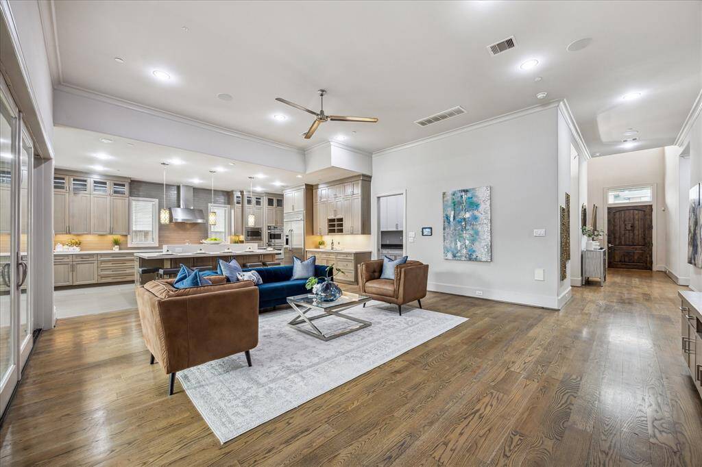 Warm wood floors add richness and character, while soaring high ceilings enhance the sense of space and openness. Soaring high ceilings enhance the sense of openness, while the seamless flow to the kitchen and surrounding spaces creates an inviting atmosphere perfect for gatherings.