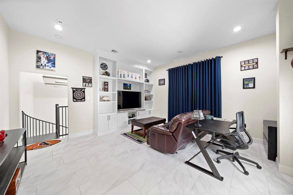 This flex space features white marble-look tile floors and a built-in media center providing abundant storage.