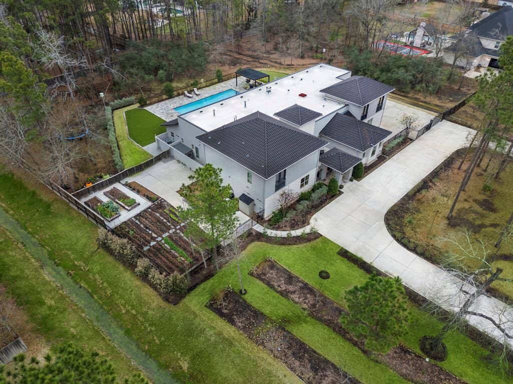 The outdoor spaces at 5211 Pine Wood Meadows Ln include an in-ground pool, vegetable garden, orchard and expansive green space on an a 2acre lot. Manicured landscaping, a security gate and private fenced yard enhance the luxurious backyard.