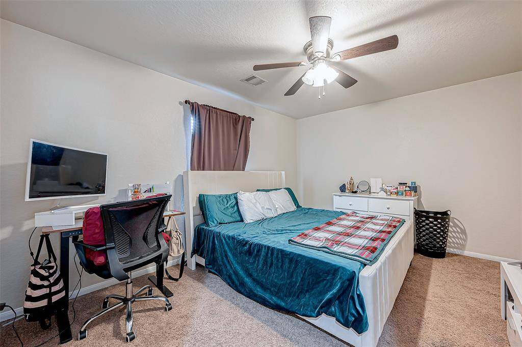 Spacious yet cozy, this bedroom offers a versatile layout suited for restful nights or productive mornings. The window brightens the space, while the soft carpet underfoot adds warmth.