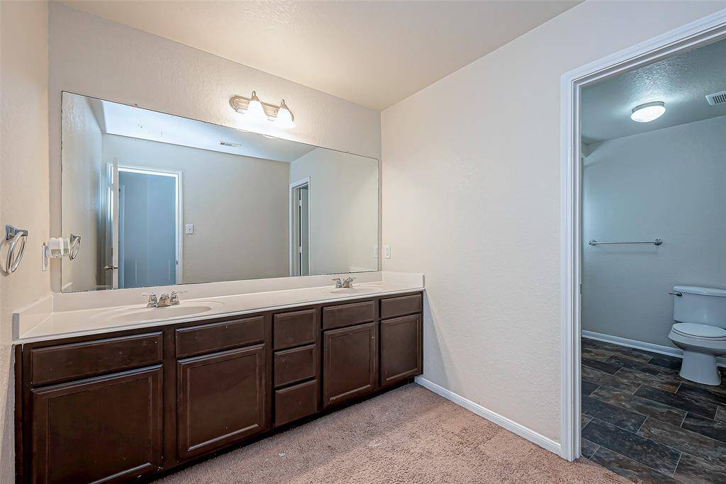 Comfortable and stylish, this full bathroom features a large vanity with dual sinks, ample cabinet storage, and elegant lighting fixtures. The separate vanity area offers added convenience for busy mornings.