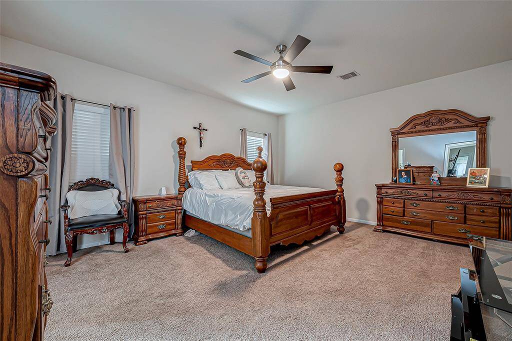 This spacious primary bedroom is beautifully illuminated by large windows, creating a bright and airy feel. The neutral walls and plush carpet provide a timeless foundation for any decor style.
