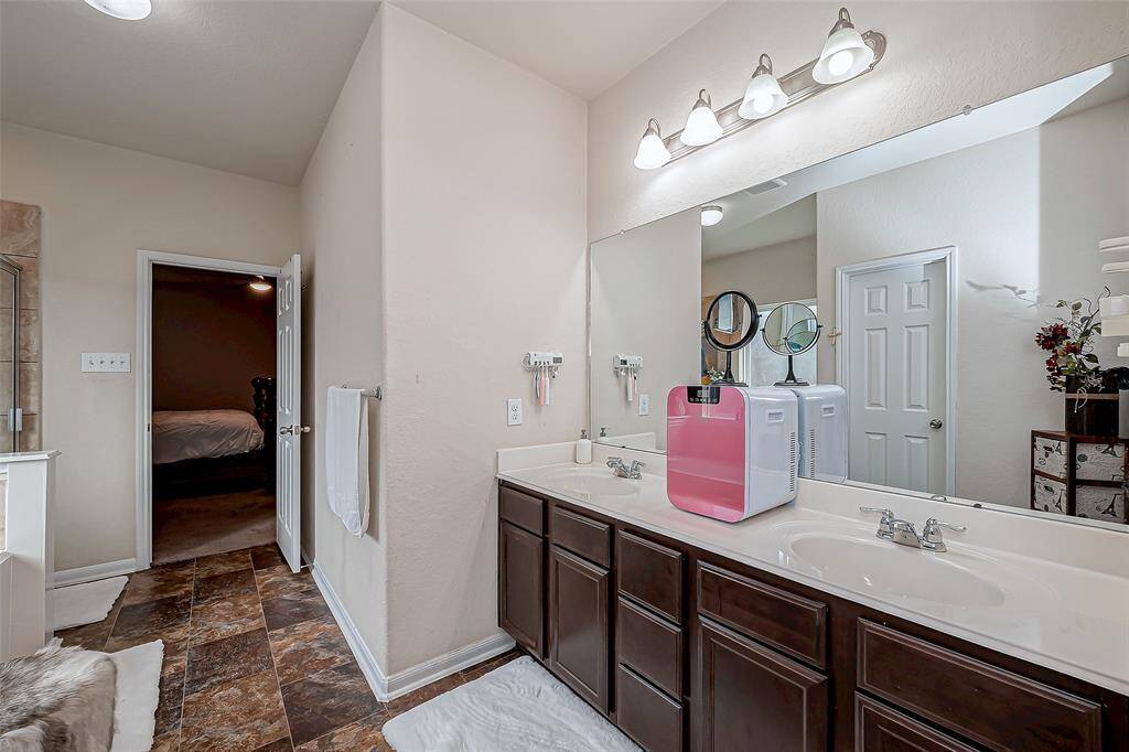 A beautifully appointed en suite bath featuring a dual-sink vanity with rich dark cabinetry.