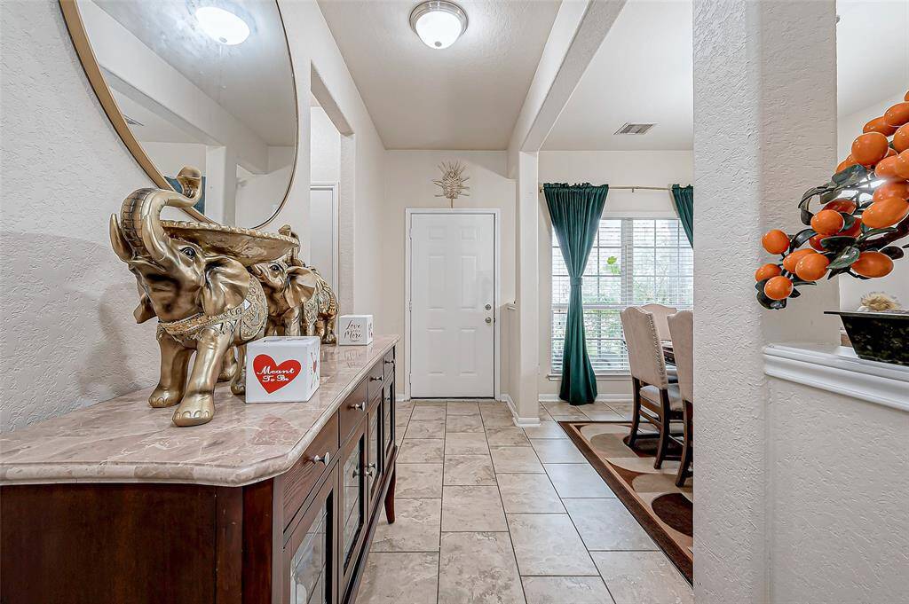 A well-lit introduction to the home, the foyer seamlessly connects to the main living spaces beyond. Subtly textured walls add depth, while the open sightlines allow for an effortless flow through the home. The formal dining area sits just to the left, offering an elegant space for meals and gatherings.
