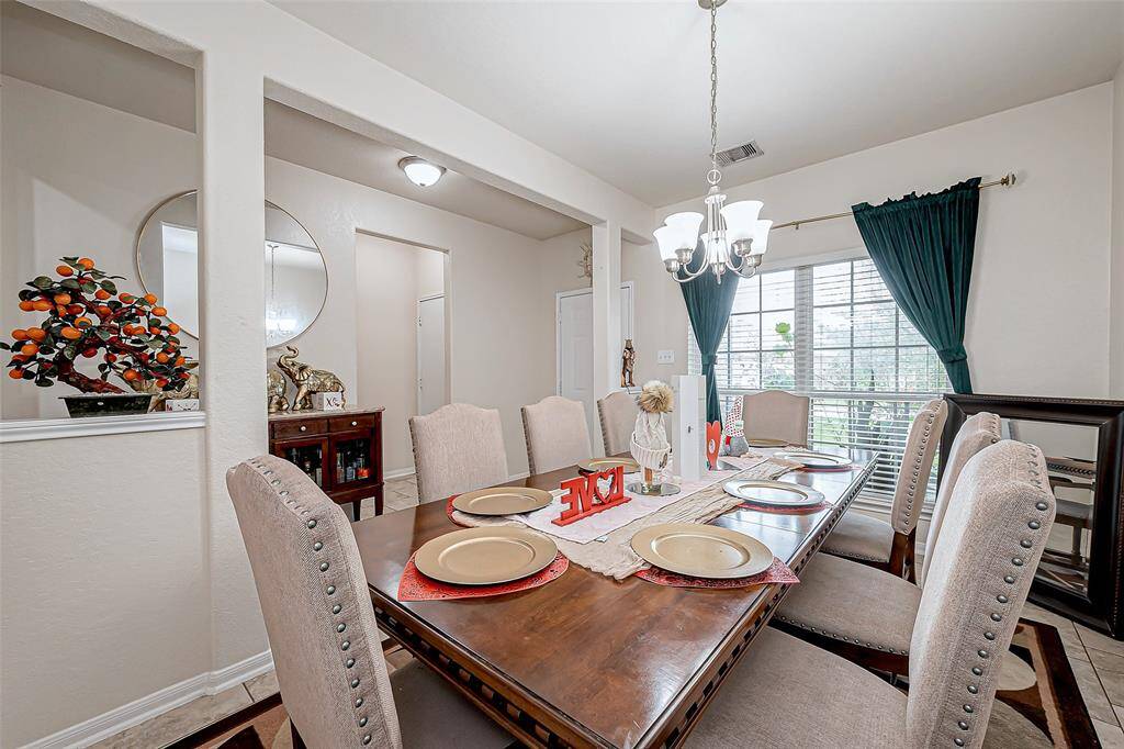 Graceful yet understated, the dining area is framed by a wide entryway that enhances its connection to the rest of the home. A chandelier adds a touch of refinement, while the large window allows natural light to highlight the space’s clean lines.