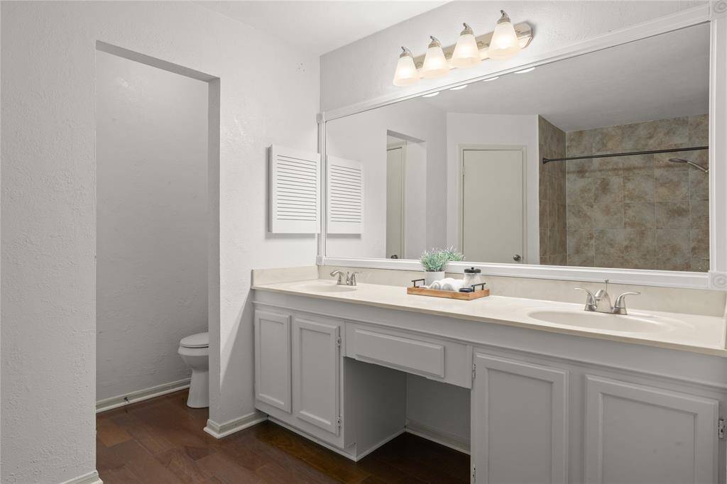 This primary bath's old mirror has been replaced by this handsomely framed, elongated mirror.  The recently installed brushed nickel faucets, shower and lighting fixtures enhance the beauty of this room.  The dual sinks flank the vanity that possesses a convenient drawer below the countertop making it a breeze to complete your look in the morning.