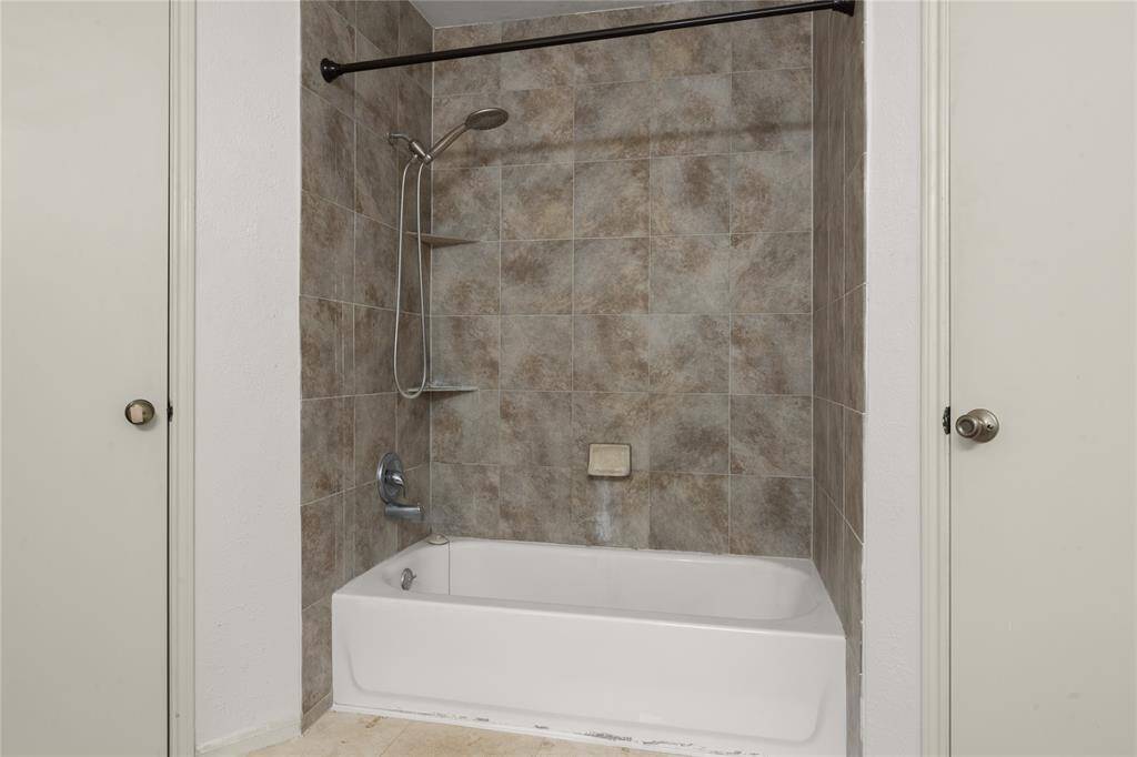Two large walk-in closets are on either side of this tub/shower combo with a handsome tile surround.