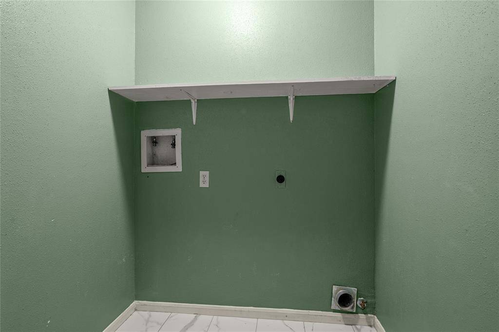 Leading from the kitchen to the garage is this spacious laundry room with electric or gas dryer connections and a handy shelf above for all your laundry products.