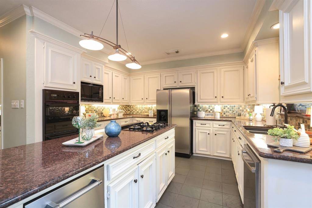 This kitchen is meant for the culinary enthusiast with a large working island that houses a gas cooktop, Kitchen Aid Ice Maker, cabinets and drawers and a granite countertop!  The pendant, with a modern flair,enhances the already great recessed and under cabinet lighting!