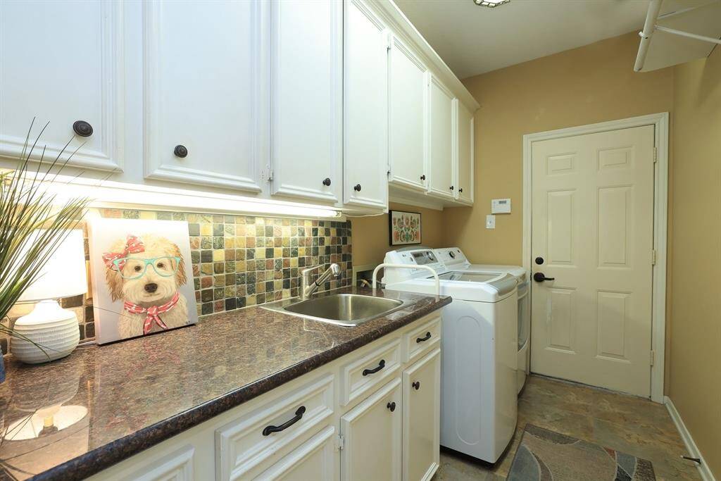The utility room is a wonderful size and is located between the garage and just off the kitchen!  No noise while sleeping!!  The spaciousness of the cabinets provides ample room for tons of cleaning supplies!  Tile flooring and granite counters along with a stainless sink for easy maintenance!