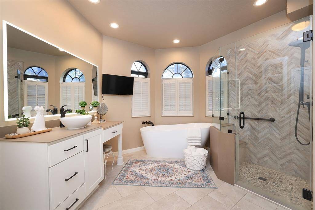 The Remodeled Primary Bath feels open and modern.  With a well-balanced design that is both classic & modern, natural stone is accented with a touch of greys and beige for a elegant and timeless look. Three arched windows overlook the back yard with plantation shutters attached.   The soaker tub is exactly what you need after a long work day!  Rest and Retreat!