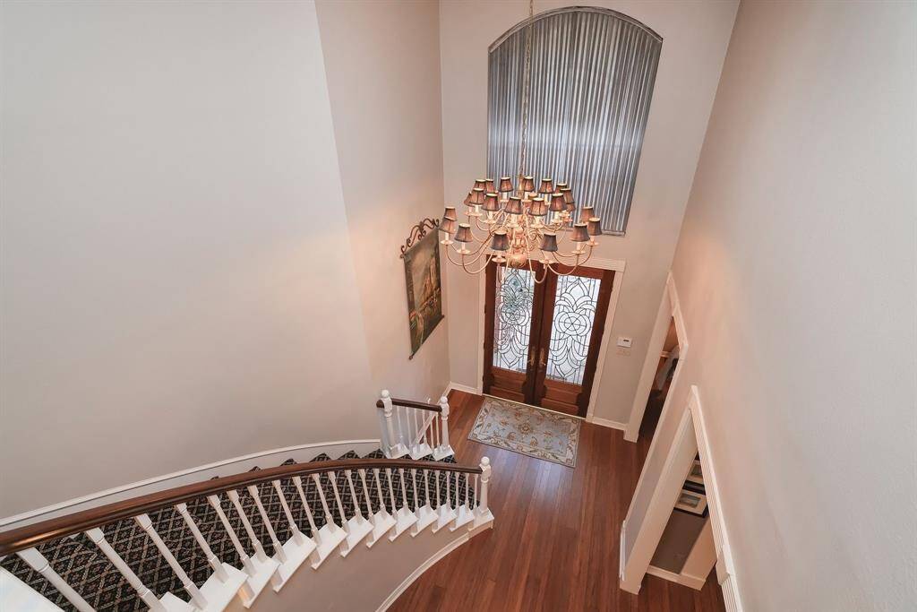 This view is from the 2nd floor landing into the entry.  Just a stunning view of the wood floors, soaring spiral stairs and palladium window above the solid lead glass front door.