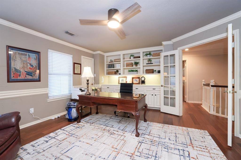 Notice the architectural details in this room!  This home is full of unique style!  Here you will see the wall unit that is built in with open shelving and cabinets.  Double doors lead to the hall and dual staircase.  To add to this fabulous room is a walk in closet (just on the left by the bookcase).
