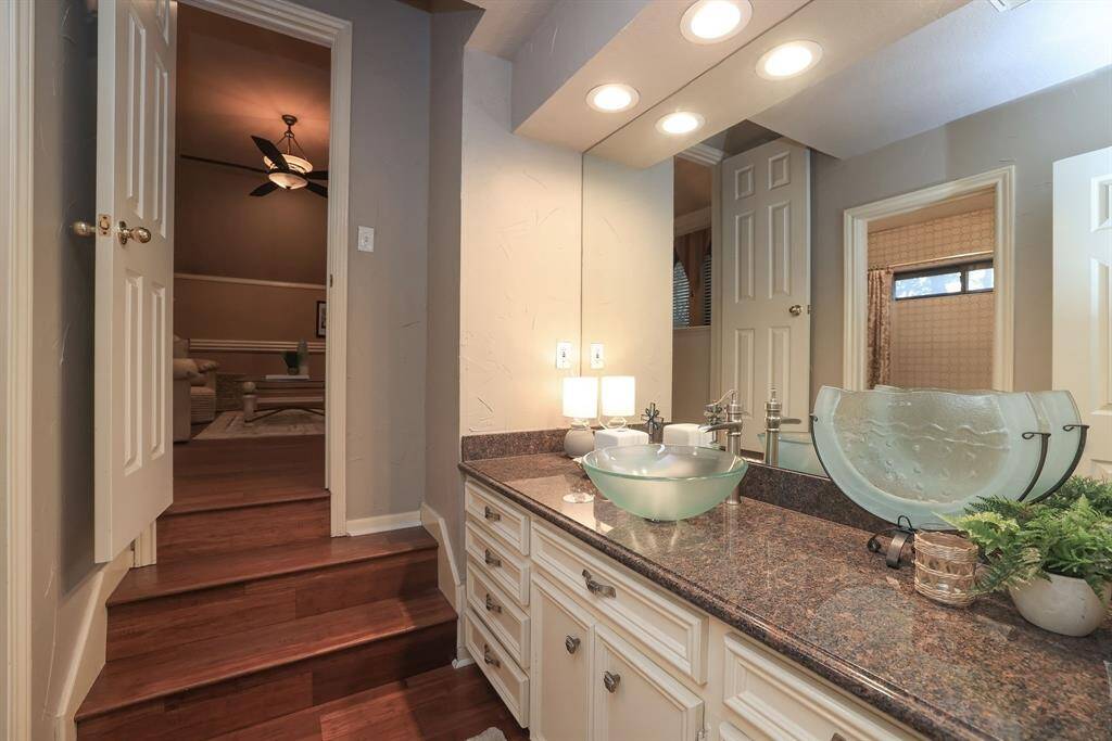 This is the full sized bath located between the game room and a secondary bedroom.  Full size vanity with cabinets and drawers, granite countertops, vessel sink, full sized mirror and recessed lighting.  As predominate through the 2nd foor, this room also has wood flooring.  Not seen is the shower/tub that has white mosaic circular tile!