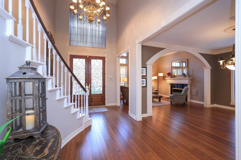 This inviting home features a bright and spacious entryway with engineered hardwood flooring, traditional décor, a large entry chandelier and an open layout leading to a beautiful living and dining room. Ample natural light enhances the welcoming atmosphere.
