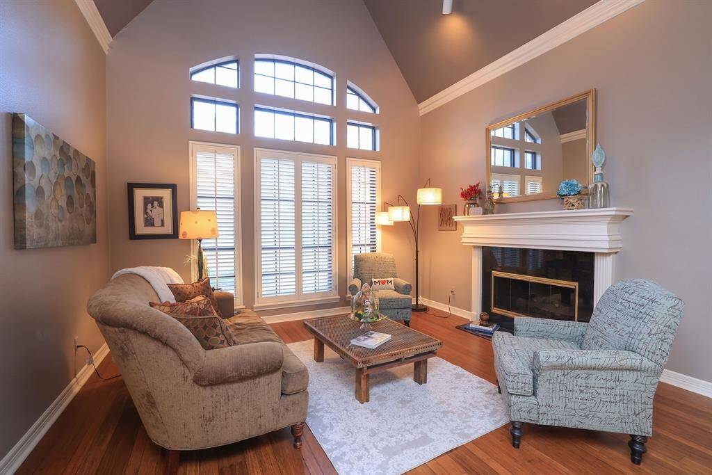 This brilliant & stylish room features elegant seating, wood floors and a classic gas burning fireplace with traditional wood mantle.  Notice the vaulted ceiling for a dramatic effect to the room, along with large windows, transom windows for added height and plantation shutters.