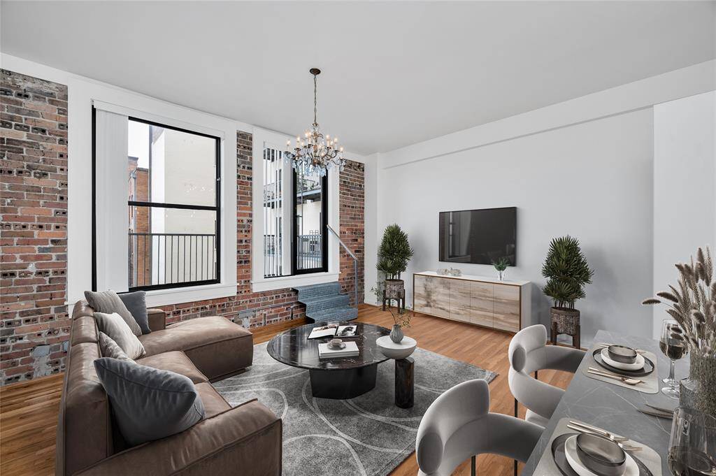 The focal point of the Living Area is the exposed brick wall which adds warmth and a sense of history to the home. Custom metal steps lead up to door to access the balcony. Vertical shades cover all windows.  PHOTO VIRTUALLY STAGED.