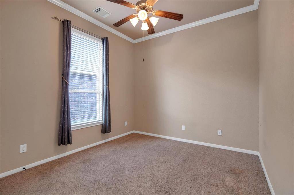 This room features neutral walls and carpet, a ceiling fan with lights, and a window with blinds and curtains, offering a cozy and versatile space.